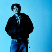 An musician called 'ThxSoMuch' posed in front of a blue backdrop